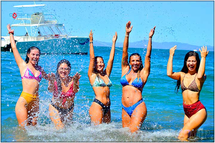 5 girls in bikinis splashing water in pacific ocean