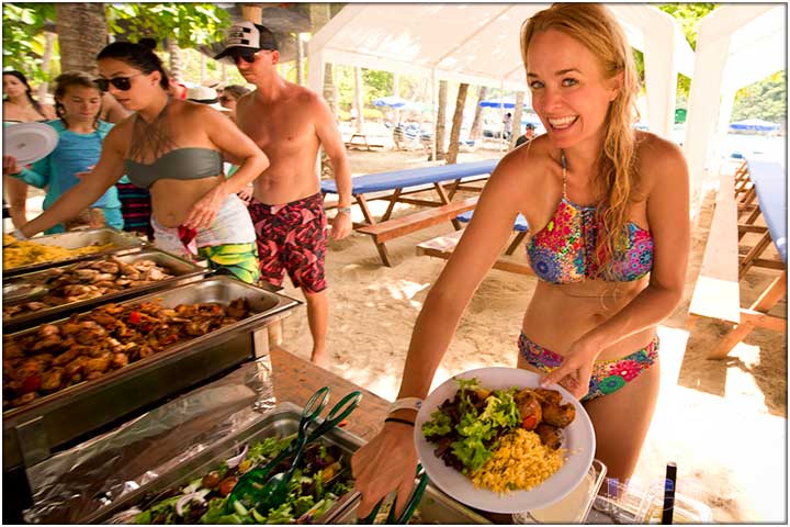 Pretty girl in bikini serving herself food at lunch buffet in Tortuga Island Costa Rica
