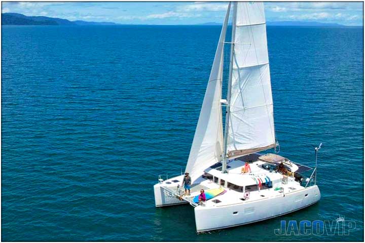 Drone view of luxury catamaran sailboat on clear blue ocean water