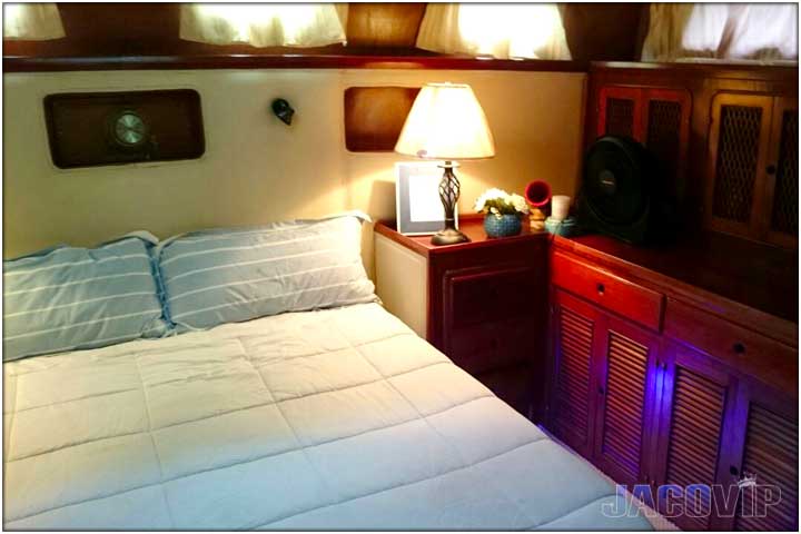 Bedroom with queen size bed and table lamps on boat