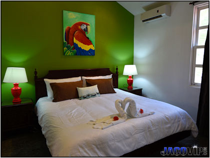 King bed and painting of Scarlett Macaw