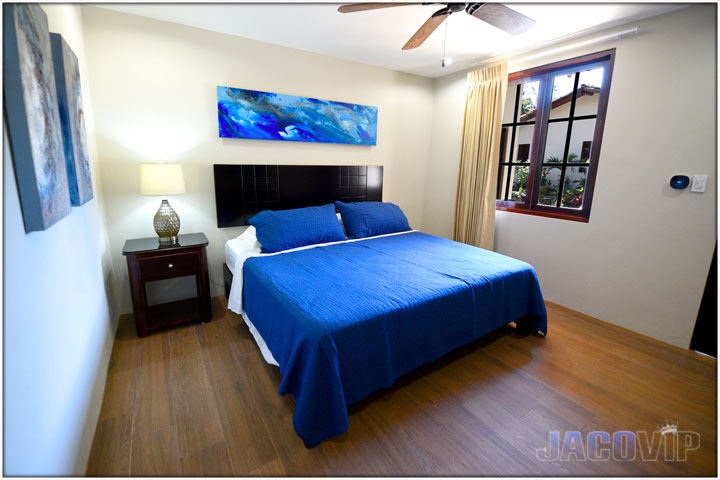 King size bed with blue bed cover and blue artwork on the wall