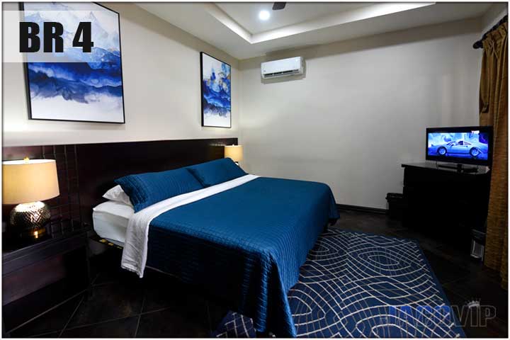 King size bed with blue cover and blue artwork on the wall