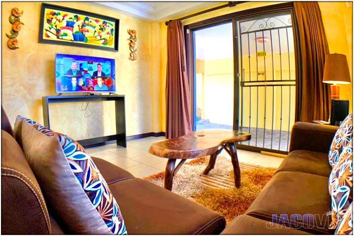 Corner view of living room sofas with rustic wood coffee table and modern tv on wall