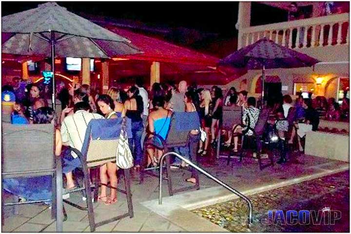 Cocal pool bar at night with people using tables and chairs