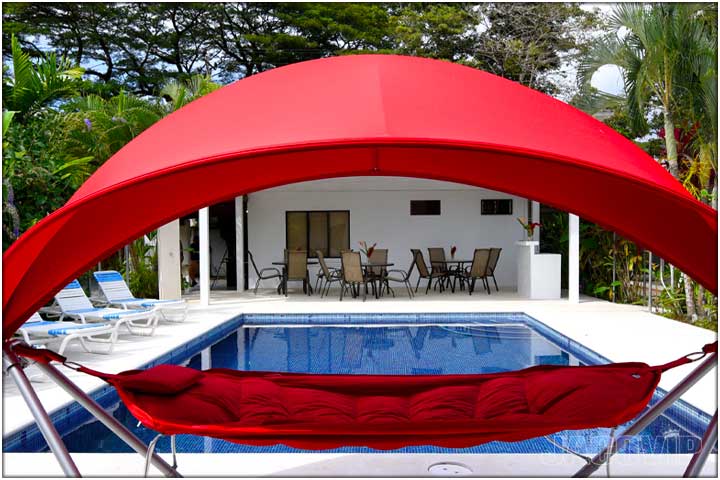 View of swimming pool through red swinging chair at La Palma