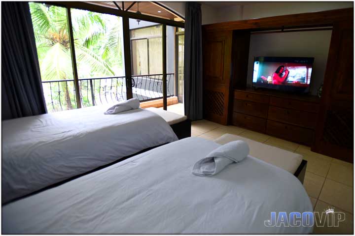 two single beds with curtains open and TV on