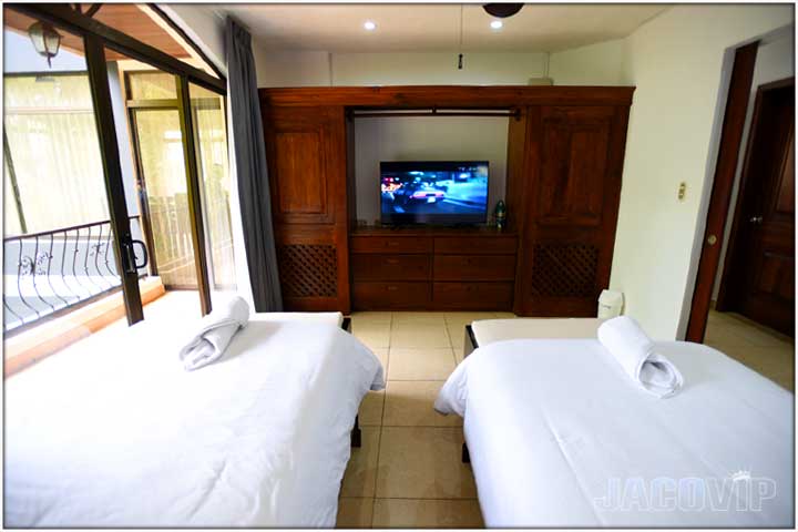 Two single beds and built in closet and TV furniture on opposite wall