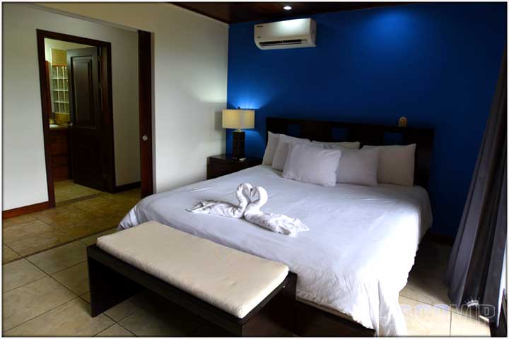 Two white bath towels shaped like swans on top of king size bed