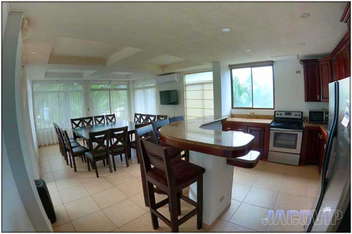 Kitchen island with bar stools and two dining tables on third floor of Pacific Palms