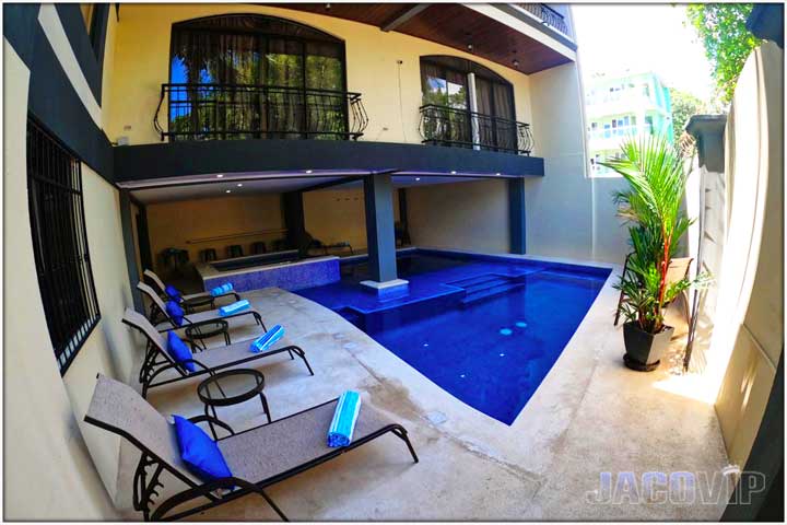 corner view of pool and deck area with lounge chairs and decorative plants
