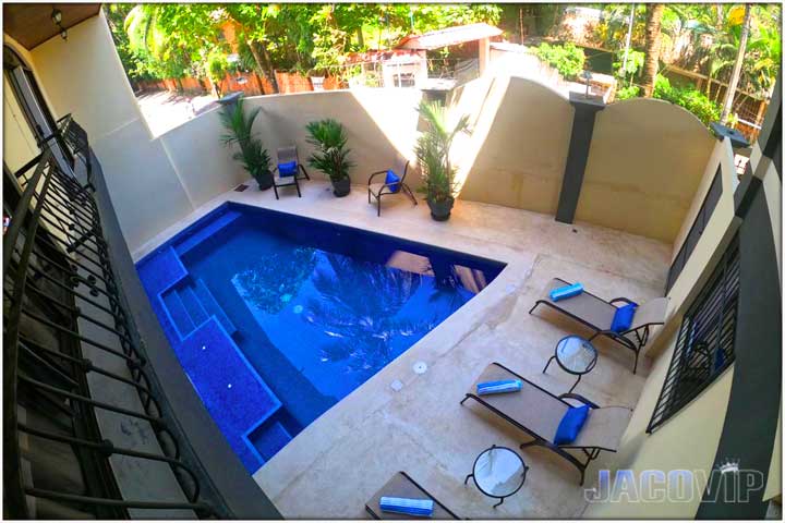 swimming pool lounge chairs and plants on deck area