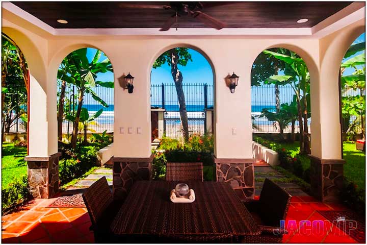 View of table and chairs looking through arches onto the beach and ocean