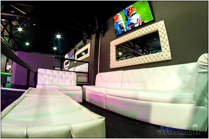 Close up of VIP section with white sofas and mirror on the wall