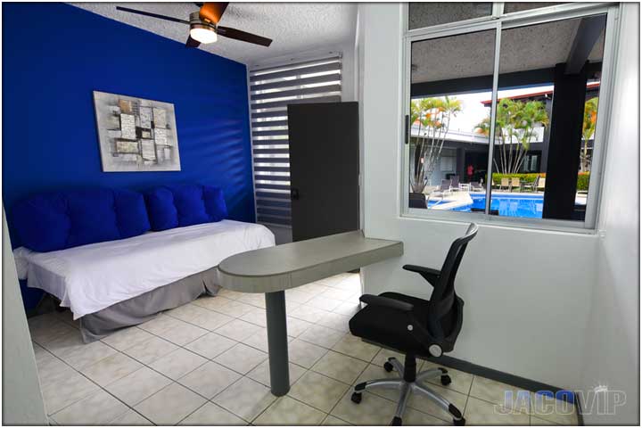 Desk and office chair next to window looking out at swimming pool