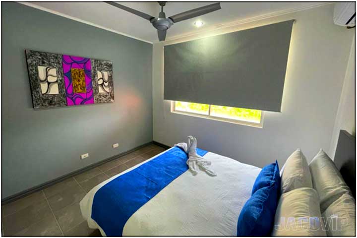 Queen size bed with white linens and blue cover runner