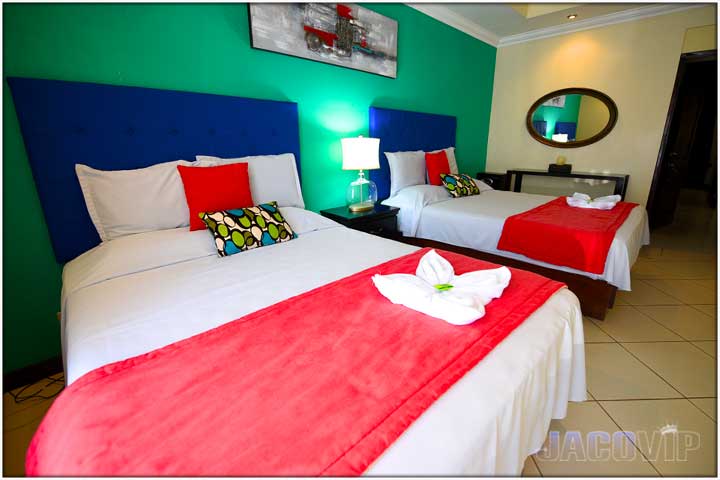 Green wall with blue headboard and red runner on queen size beds