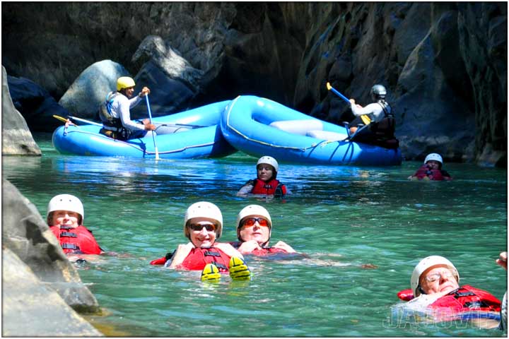 Close up of people in river and rafts in the background