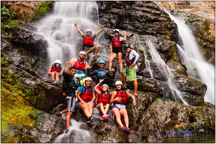 Large family group sitting on waterfall rocks